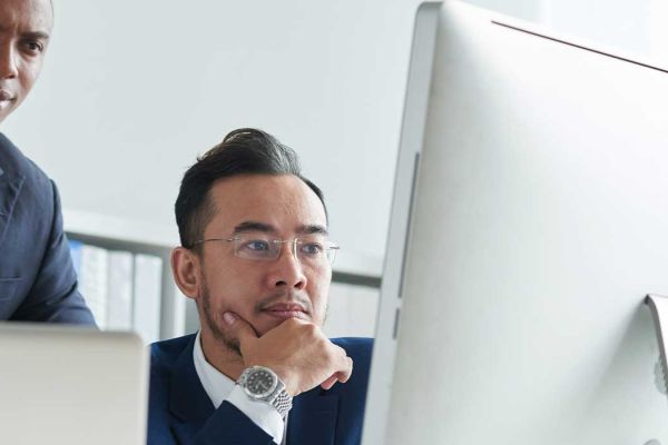 A well dressed man looking at a computer.